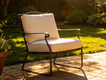 Black metal spring‑base outdoor patio chair with thick beige cushions, placed on brick paving in sunlit backyard garden